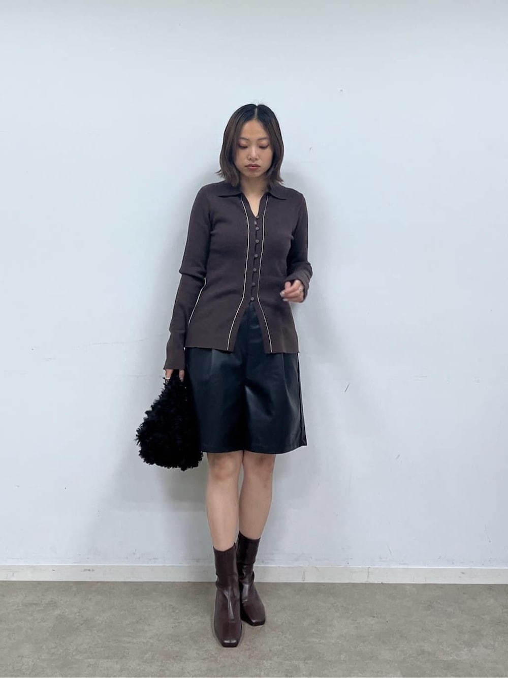 ブラウン系のニット/セーター、ブラック系のその他パンツ、ブラック系のブーツを着用したレディースの秋コーディネートの2枚目の写真
