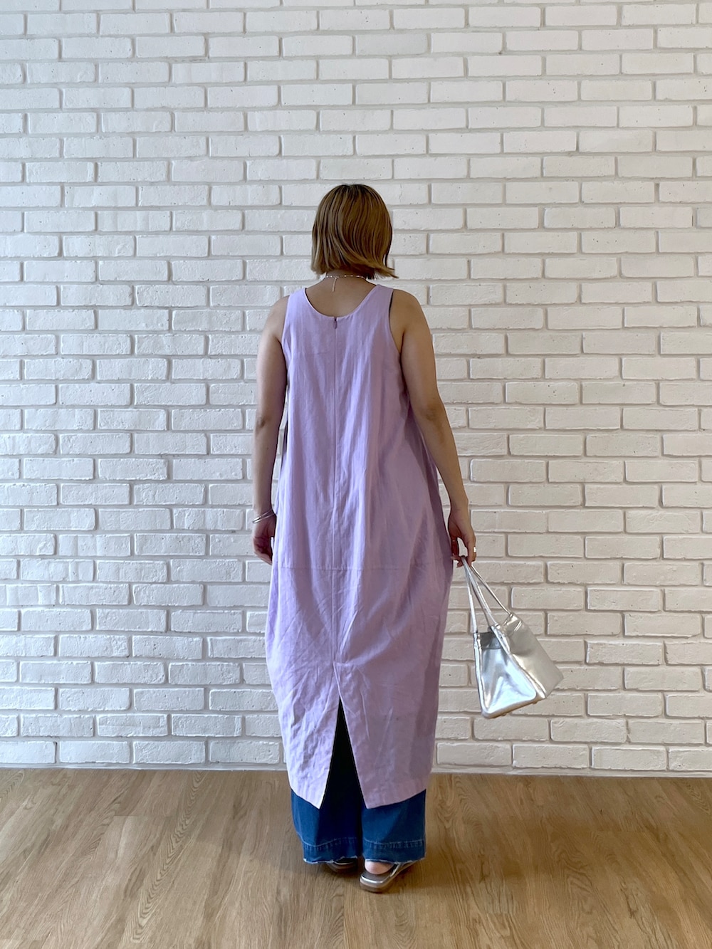 パープル系のワンピース、ブルー系のデニムパンツ、シルバー系のサンダルを着用したレディースの春コーディネートの4枚目の写真
