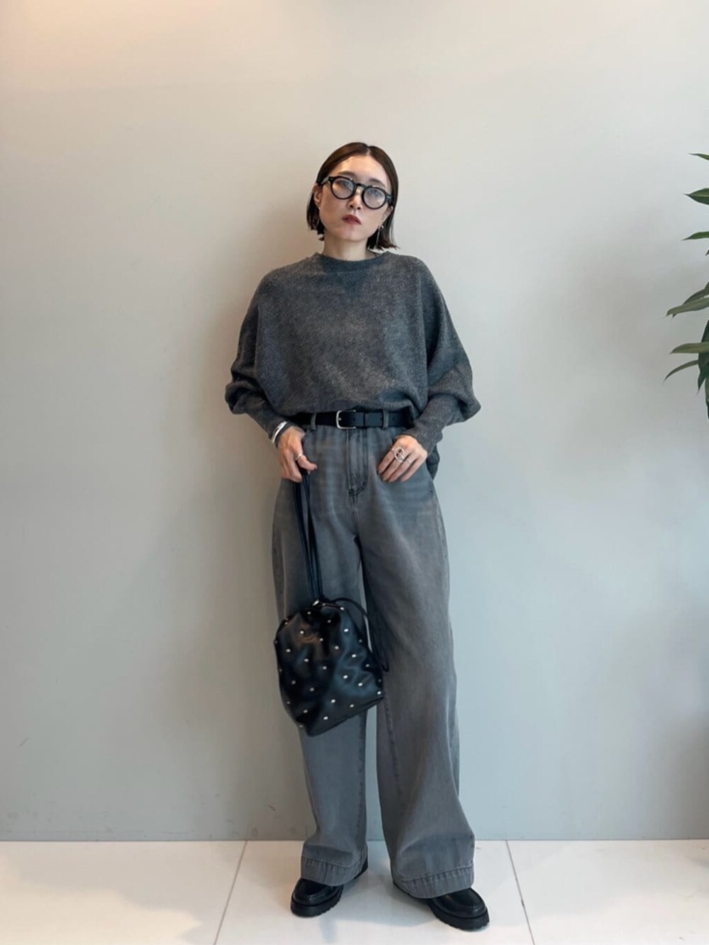 ブラック系のハンドバッグ、グレー系のデニムパンツ、グレー系のニット/セーターを着用したレディースの秋コーディネートの3枚目の写真