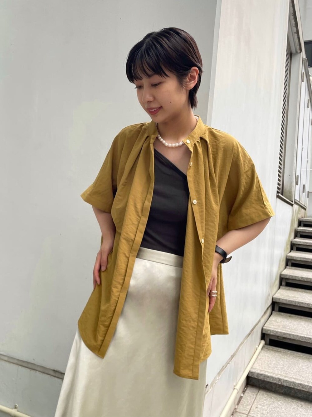 シルバー系のスカート、イエロー系のシャツ/ブラウス、ブラック系のサンダルを着用したレディースの夏コーディネートの4枚目の写真