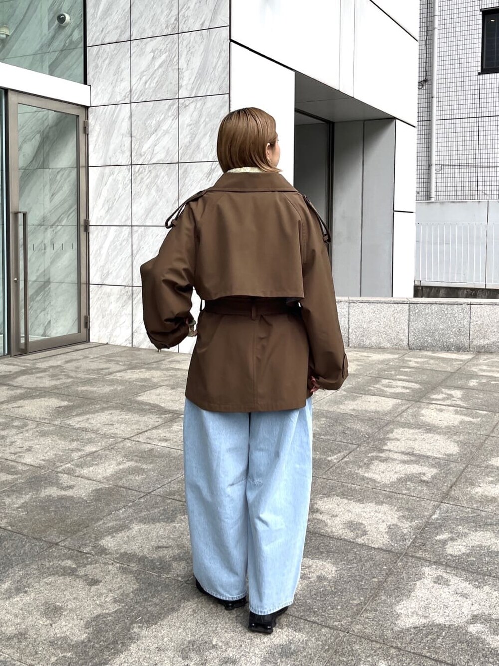 ブラウン系のトレンチコート、ブルー系のデニムジャケット、グリーン系のニット/セーターを着用したレディースの春コーディネートの3枚目の写真