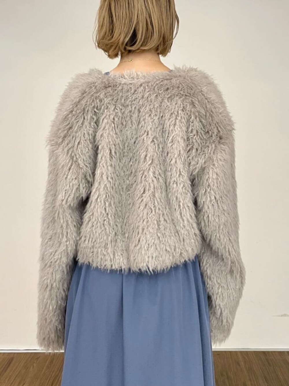 グレー系のノーカラージャケット、ブルー系のワンピース、シルバー系のブーツを着用したレディースの秋コーディネートの4枚目の写真