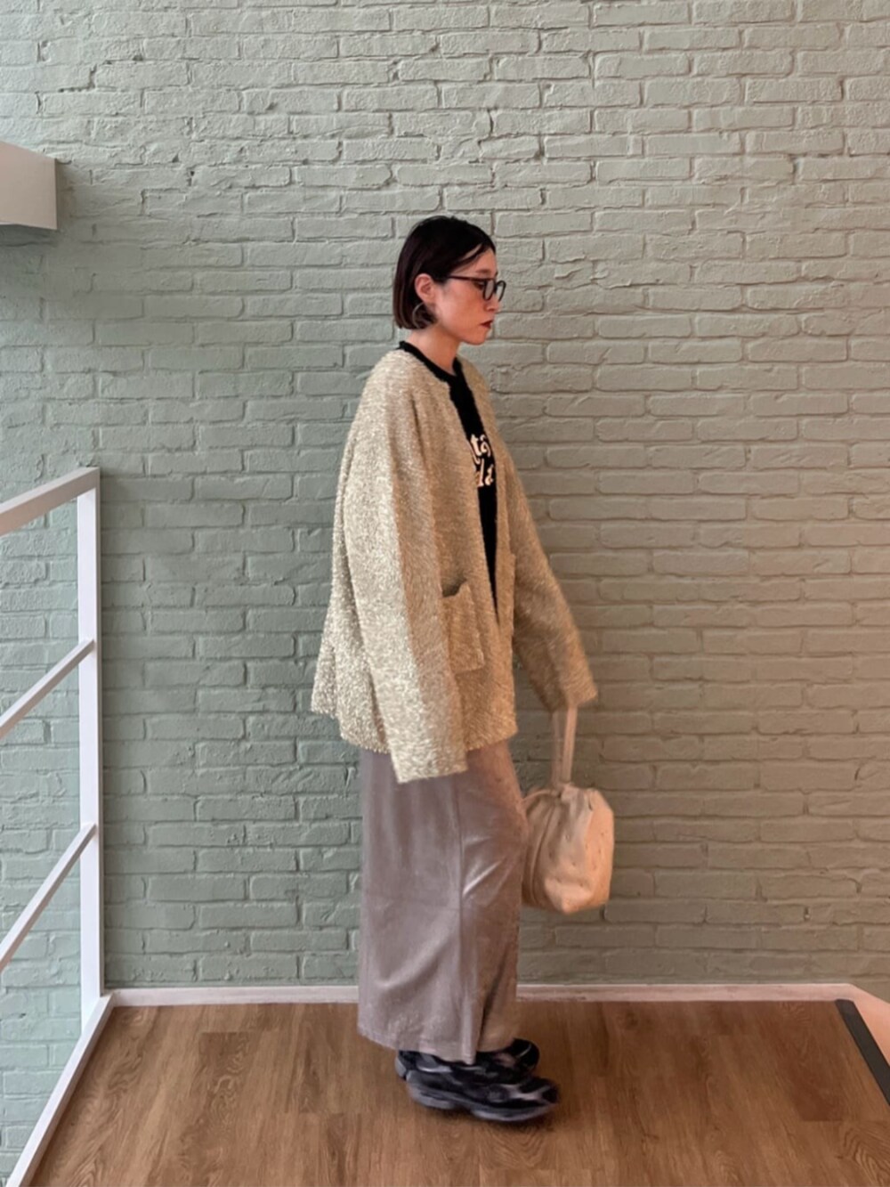 シルバー系のスカート、ブラック系のTシャツ/カットソー、ホワイト系のハンドバッグを着用したレディースの秋コーディネートの2枚目の写真