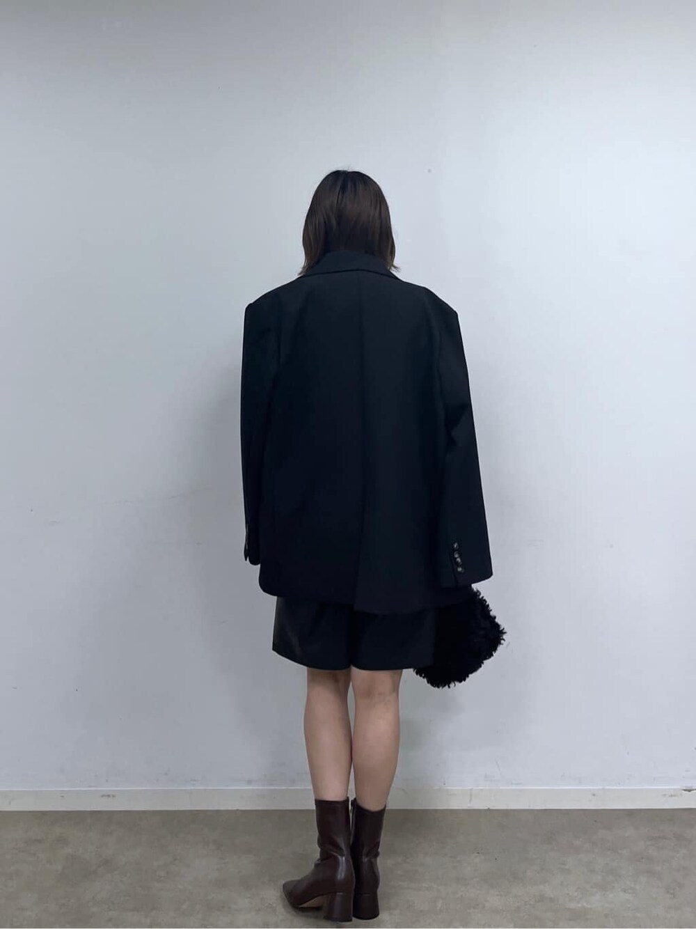 ブラック系のテーラードジャケット、ブラウン系のニット/セーター、ブラック系のその他パンツを着用したレディースの秋コーディネートの4枚目の写真