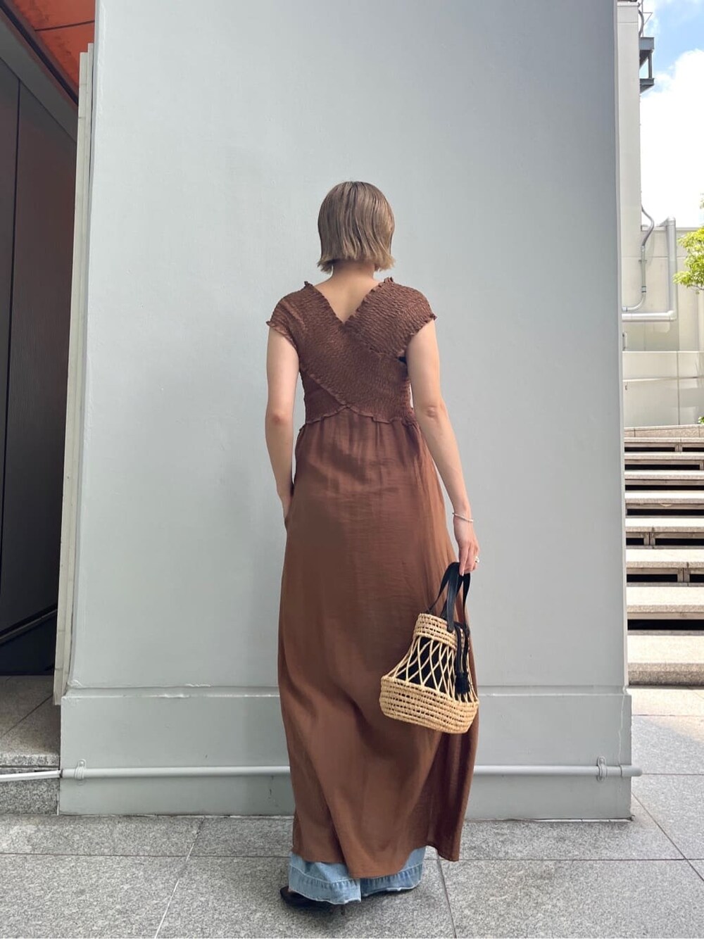 ブラウン系のワンピース、ブルー系のデニムパンツ、ブラック系のハンドバッグを着用したレディースの夏コーディネートの4枚目の写真