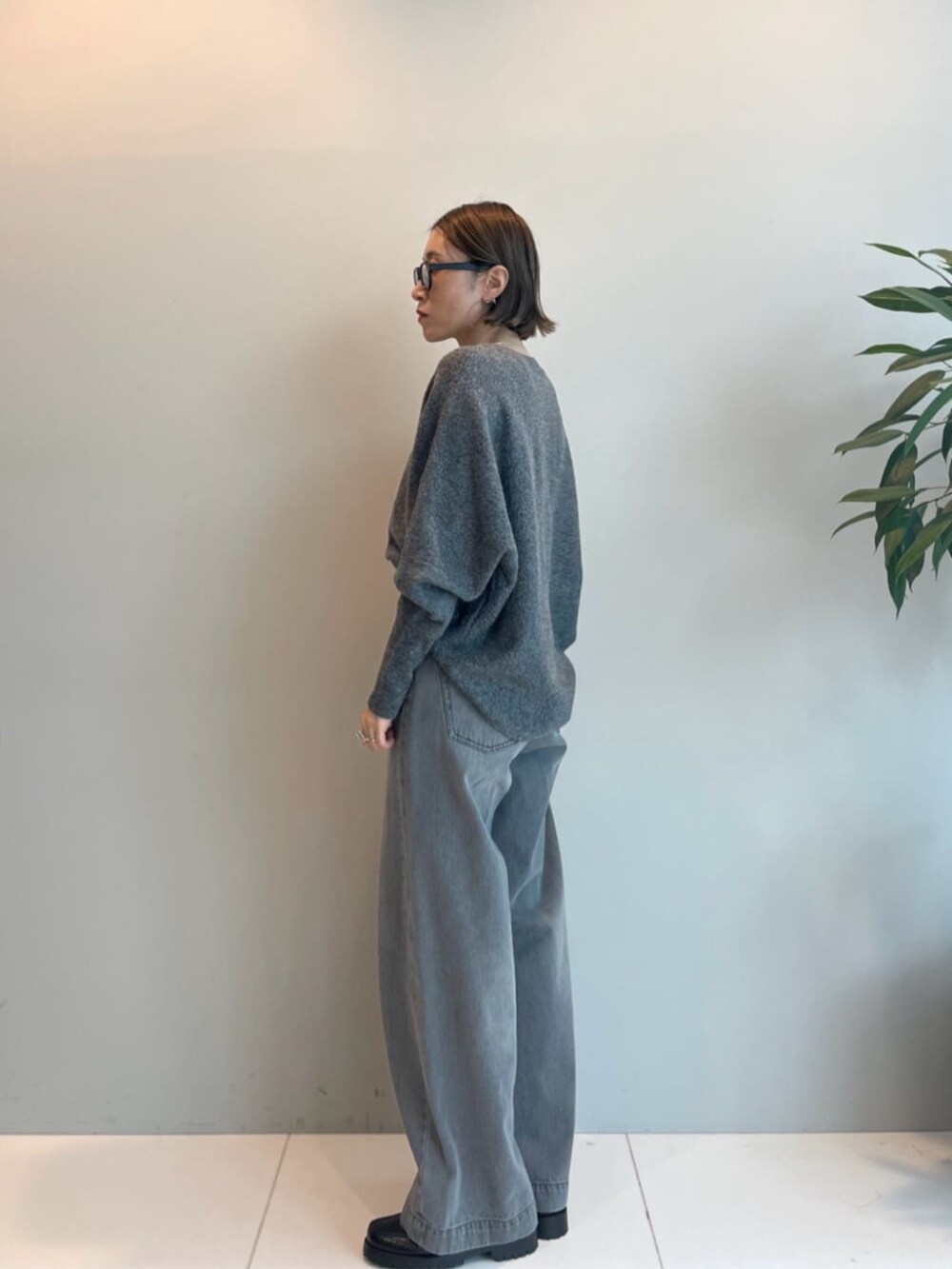 ブラック系のハンドバッグ、グレー系のデニムパンツ、グレー系のニット/セーターを着用したレディースの秋コーディネートの2枚目の写真