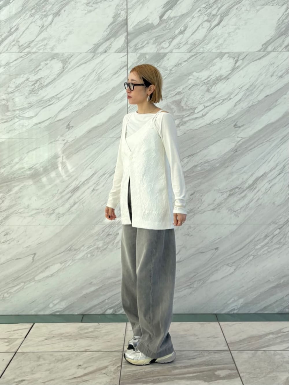 グレー系のデニムパンツ、ホワイト系のTシャツ/カットソー、ホワイト系のベストを着用したレディースの春コーディネートの2枚目の写真