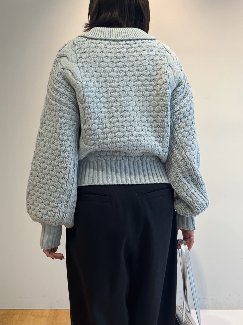 ブルー系のニット/セーター、ブラック系のその他パンツ、シルバー系のハンドバッグを着用したレディースの秋コーディネートの7枚目の写真