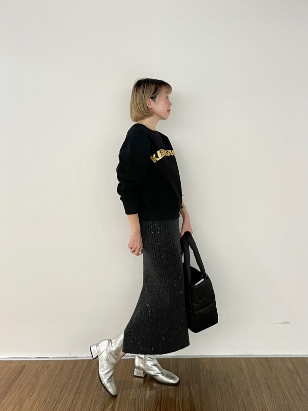 グレー系のスカート、ブラック系のスウェット、ブラック系のトートバッグを着用したレディースの秋コーディネートの2枚目の写真