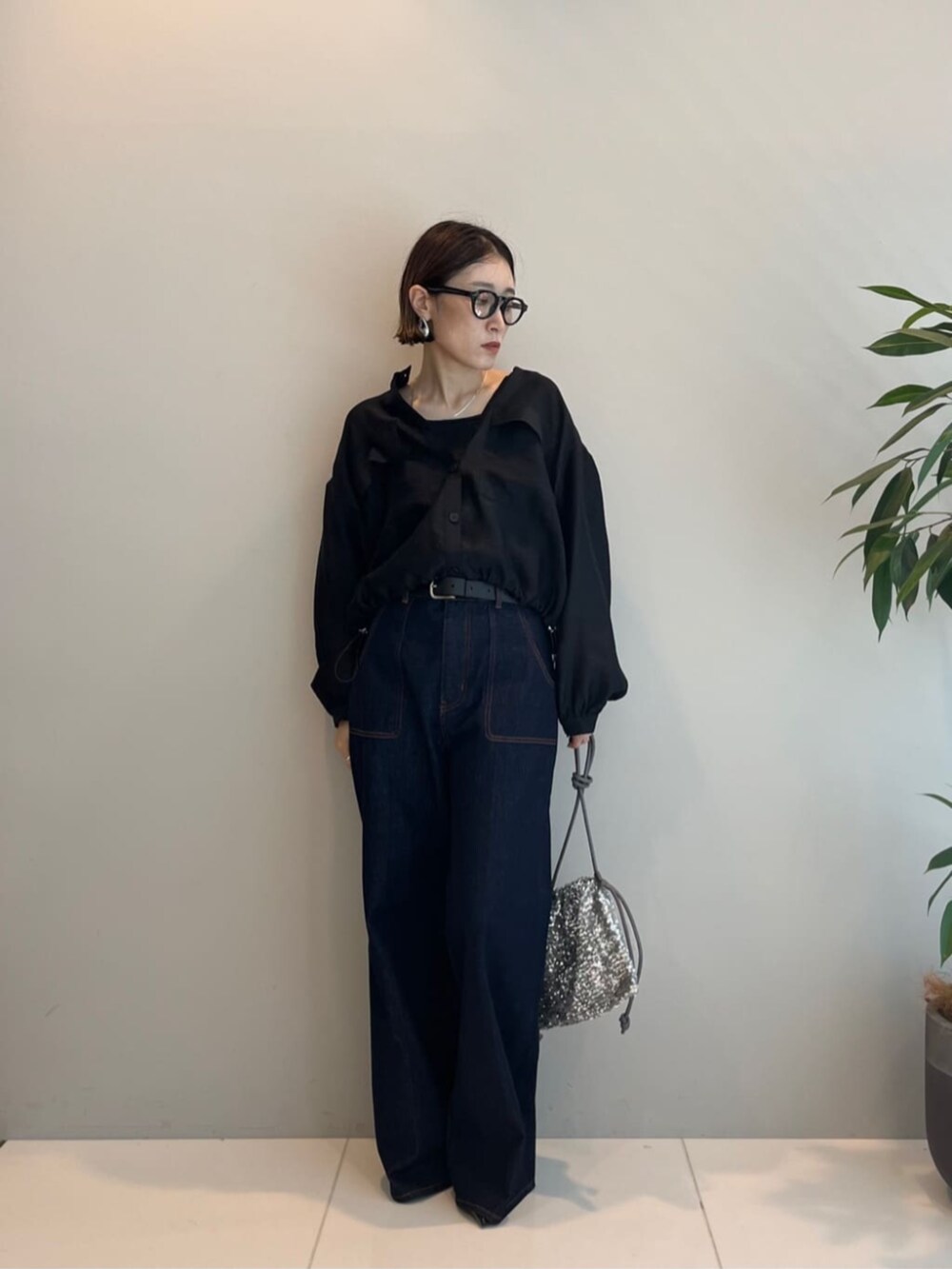 シルバー系のショルダーバッグ、ブルー系のデニムパンツ、ブラック系のシャツ/ブラウスを着用したレディースの秋コーディネートの2枚目の写真