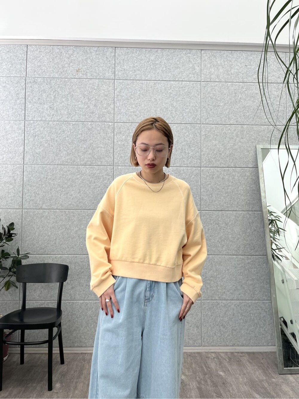 オレンジ系のスウェット、ブルー系のデニムパンツを着用したレディースの春コーディネートの5枚目の写真