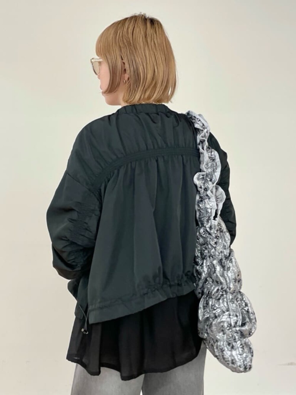 グレー系のデニムパンツ、ホワイト系のニット/セーター、グレー系のブルゾンを着用したレディースの春コーディネートの6枚目の写真