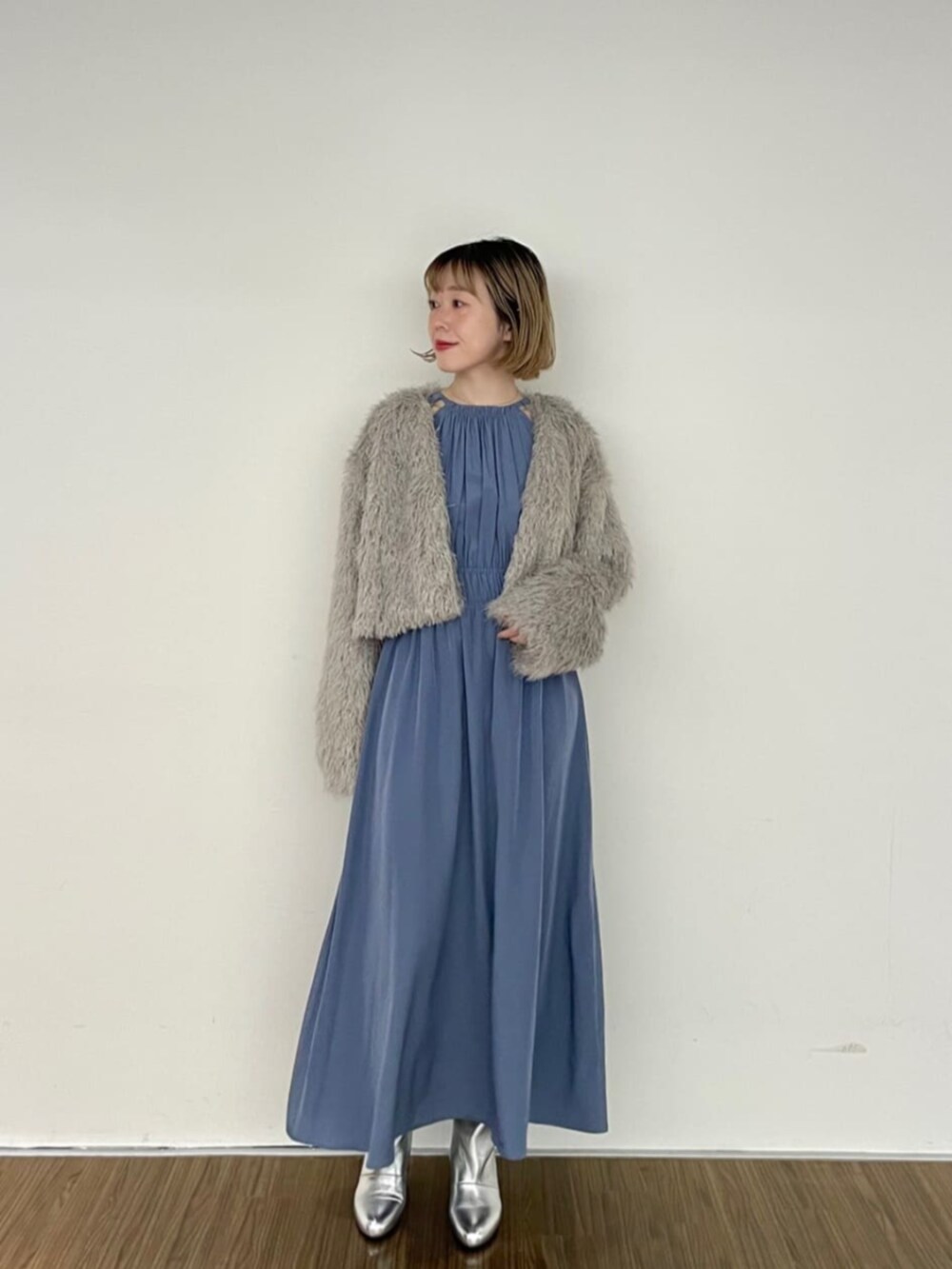 グレー系のノーカラージャケット、ブルー系のワンピース、シルバー系のブーツを着用したレディースの秋コーディネートの2枚目の写真