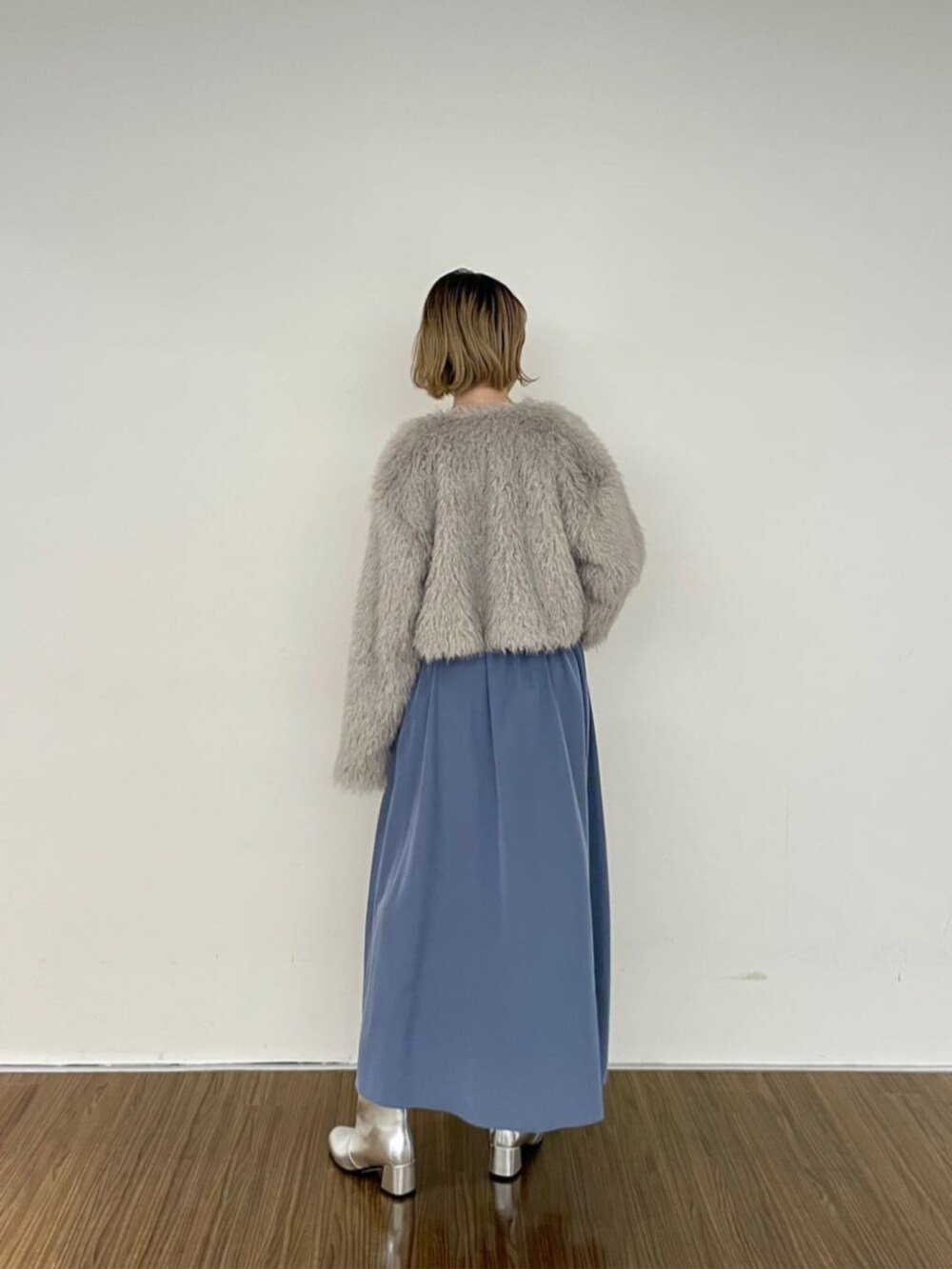 グレー系のノーカラージャケット、ブルー系のワンピース、シルバー系のブーツを着用したレディースの秋コーディネートの3枚目の写真