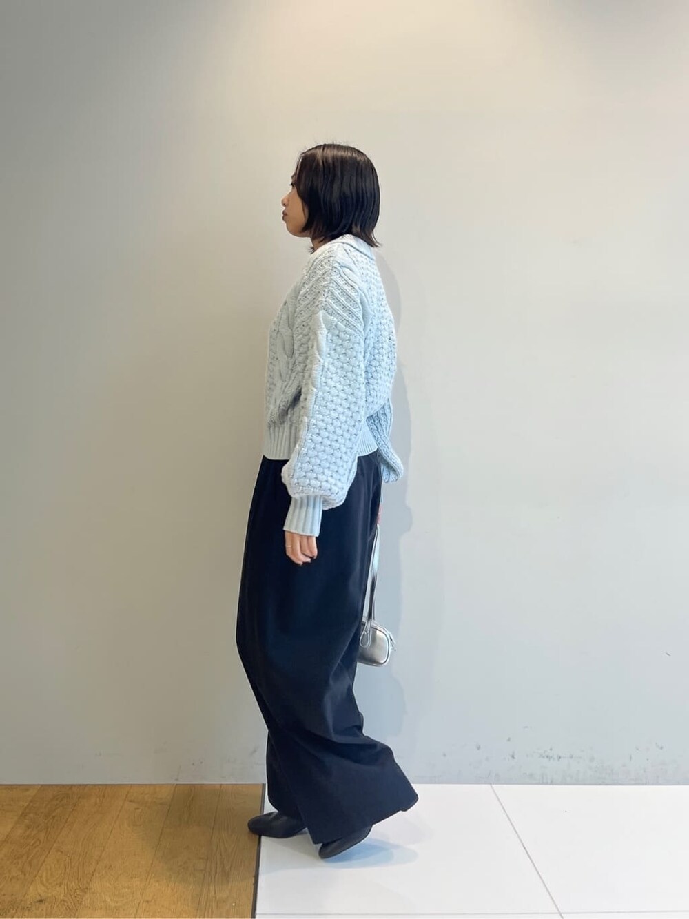 ブルー系のニット/セーター、ブラック系のその他パンツ、シルバー系のハンドバッグを着用したレディースの秋コーディネートの3枚目の写真