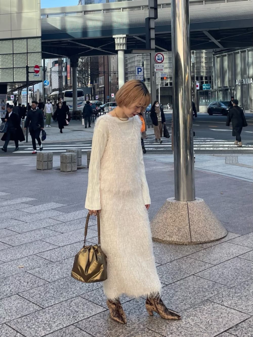 ホワイト系のニット/セーター、ブラウン系のブーツ、ホワイト系のスカートを着用したレディースの冬コーディネートの2枚目の写真