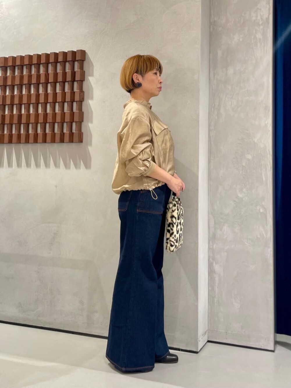 ブルー系のデニムパンツ、ブラウン系のハンドバッグ、ベージュ系のシャツ/ブラウスを着用したレディースの秋コーディネートの2枚目の写真