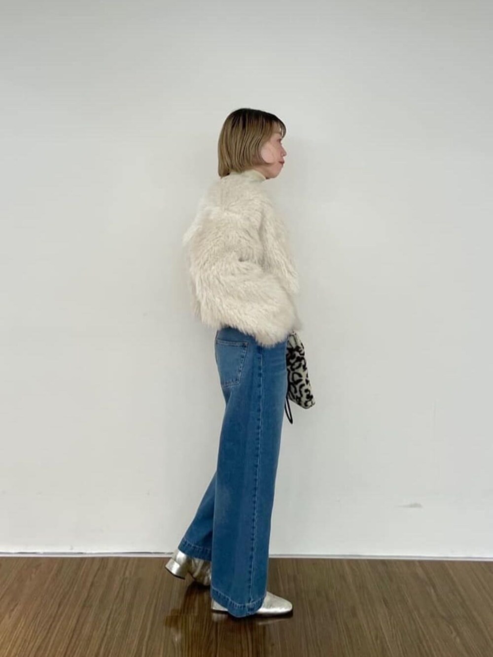 ブラウン系のハンドバッグ、ブルー系のデニムパンツ、ゴールド系のニット/セーターを着用したレディースの秋コーディネートの4枚目の写真