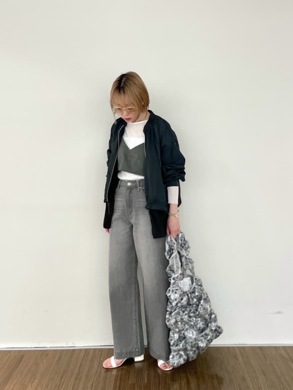 グレー系のデニムパンツ、ホワイト系のニット/セーター、グレー系のブルゾンを着用したレディースの春コーディネートの2枚目の写真