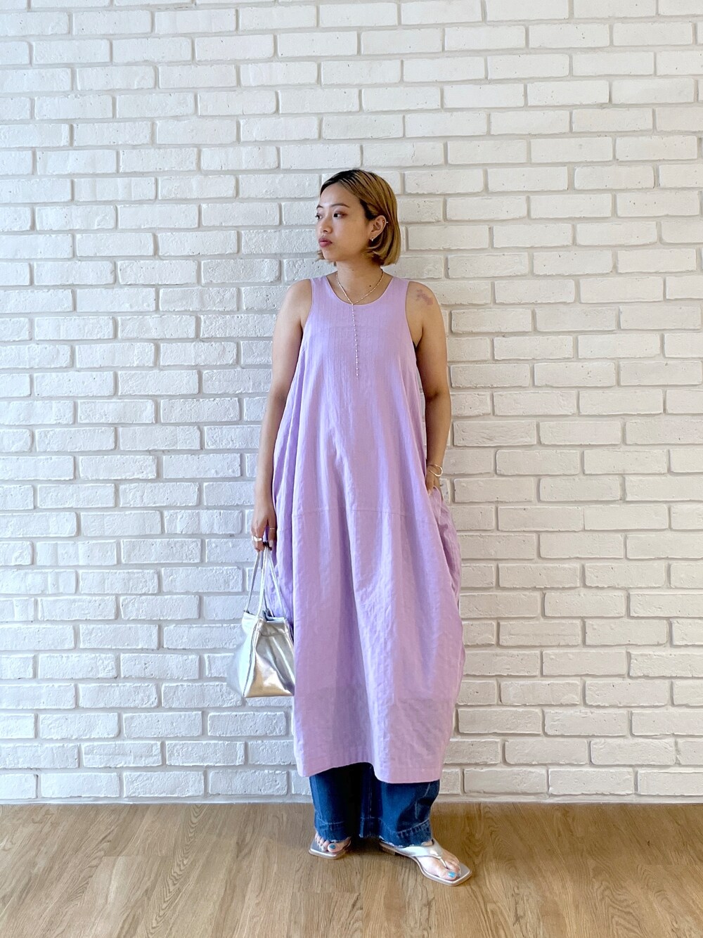 パープル系のワンピース、ブルー系のデニムパンツ、シルバー系のサンダルを着用したレディースの春コーディネートの5枚目の写真