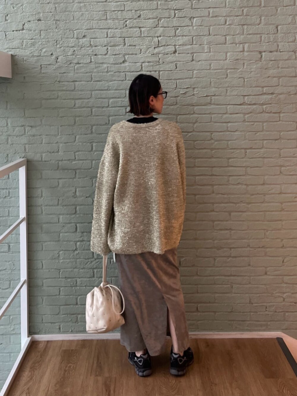 シルバー系のスカート、ブラック系のTシャツ/カットソー、ホワイト系のハンドバッグを着用したレディースの秋コーディネートの3枚目の写真