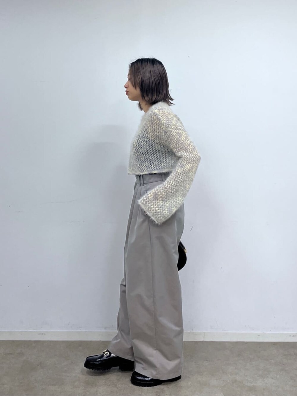 ベージュ系のニット/セーター、グレー系のその他パンツ、ブラック系のショルダーバッグを着用したレディースの冬コーディネートの3枚目の写真