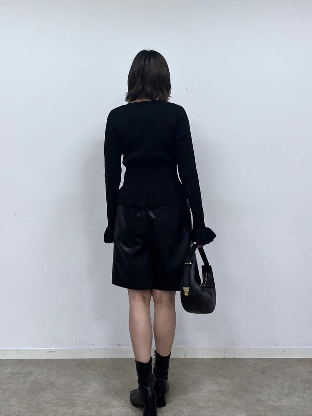 ブラック系のニット/セーター、ブラック系のその他パンツ、ブラック系のハンドバッグを着用したレディースの秋コーディネートの5枚目の写真
