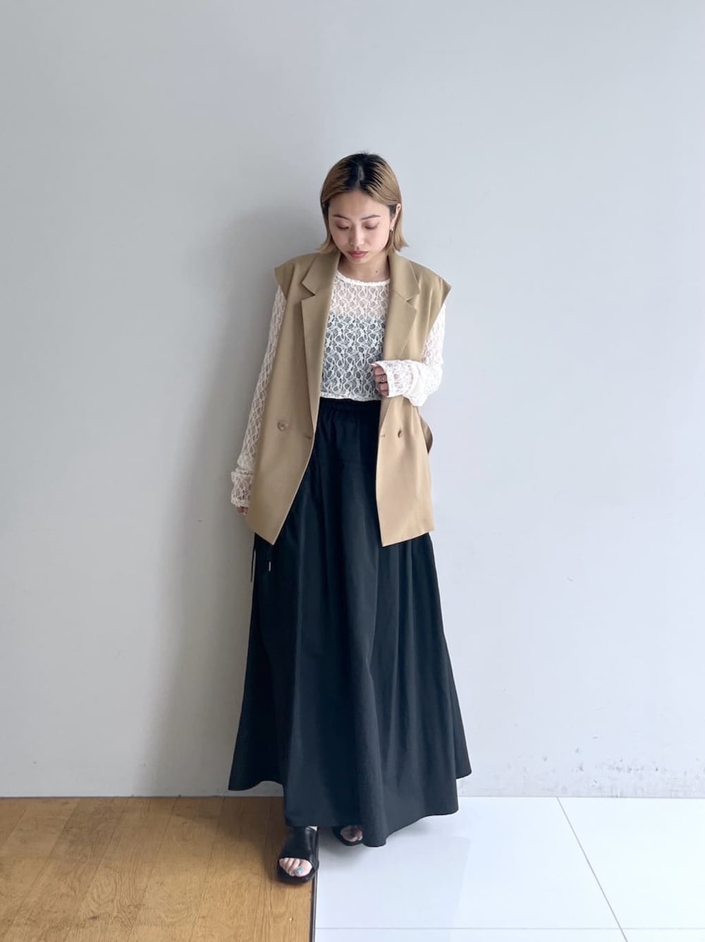 イエロー系のベスト、ホワイト系のTシャツ/カットソー、グレー系のスカートを着用したレディースの春コーディネートの7枚目の写真