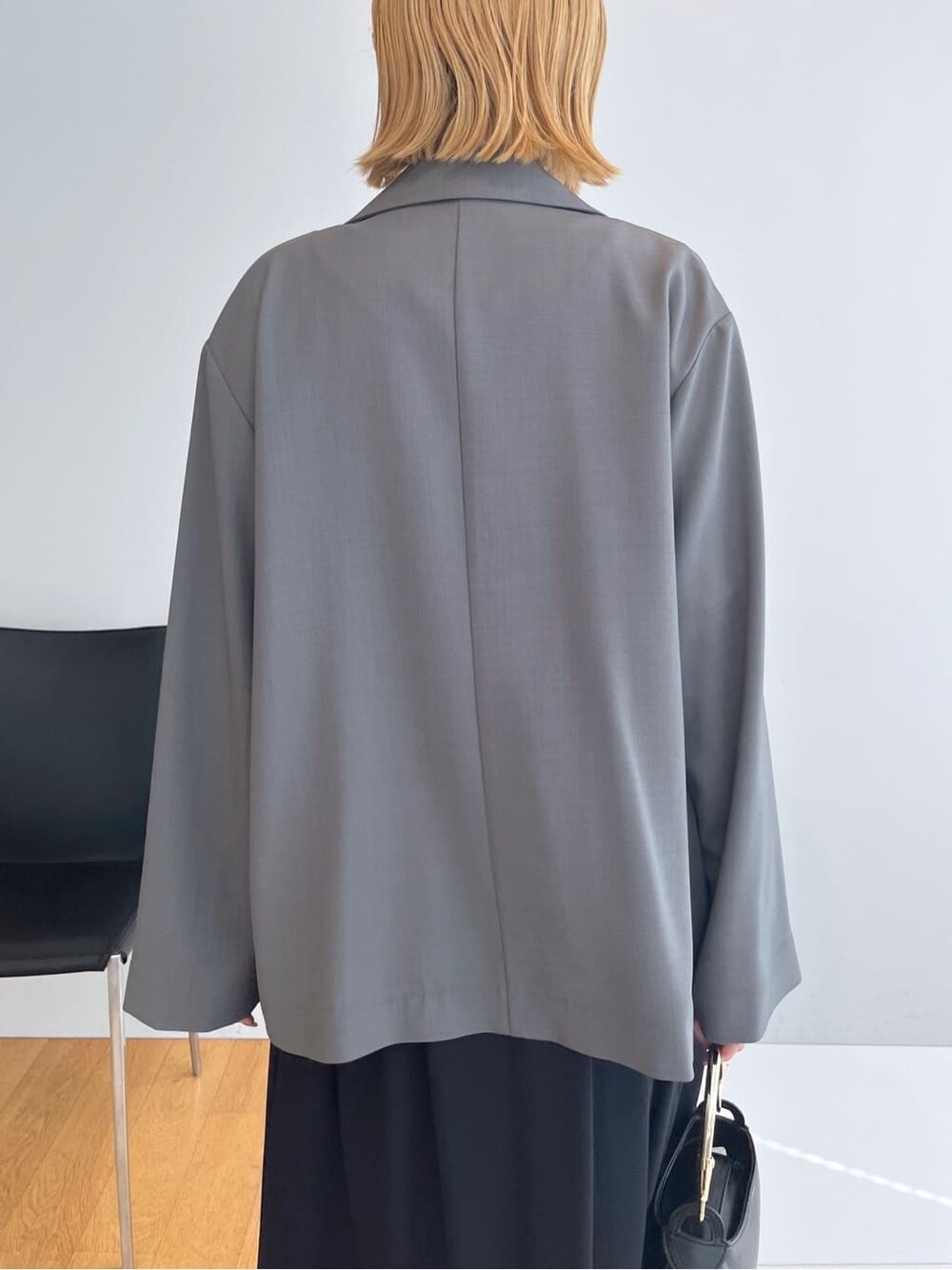 グレー系のテーラードジャケット、グレー系のニット/セーター、ブラック系のスカートを着用したレディースの春コーディネートの7枚目の写真