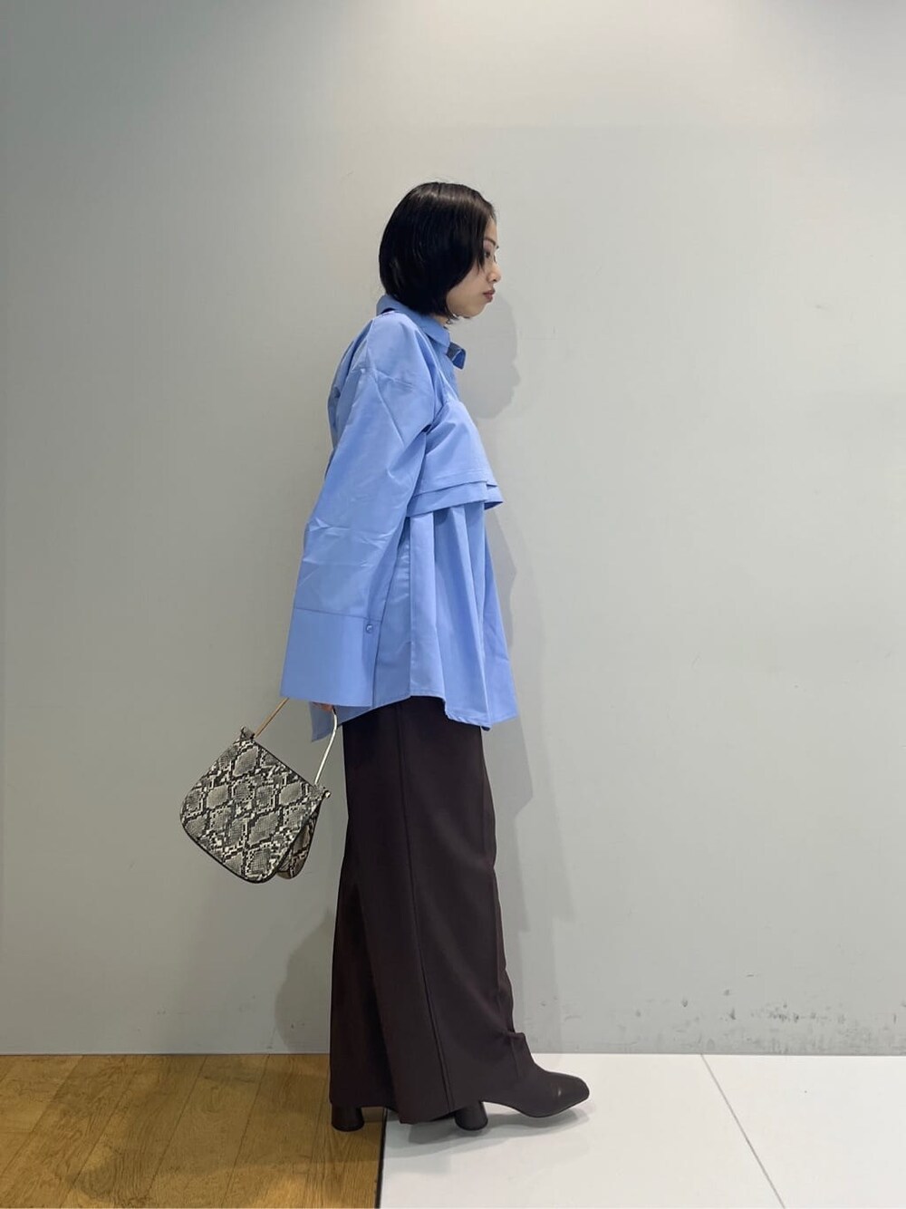 ブルー系のシャツ/ブラウス、ブラウン系のその他パンツ、グレー系のショルダーバッグを着用したレディースの秋コーディネートの2枚目の写真