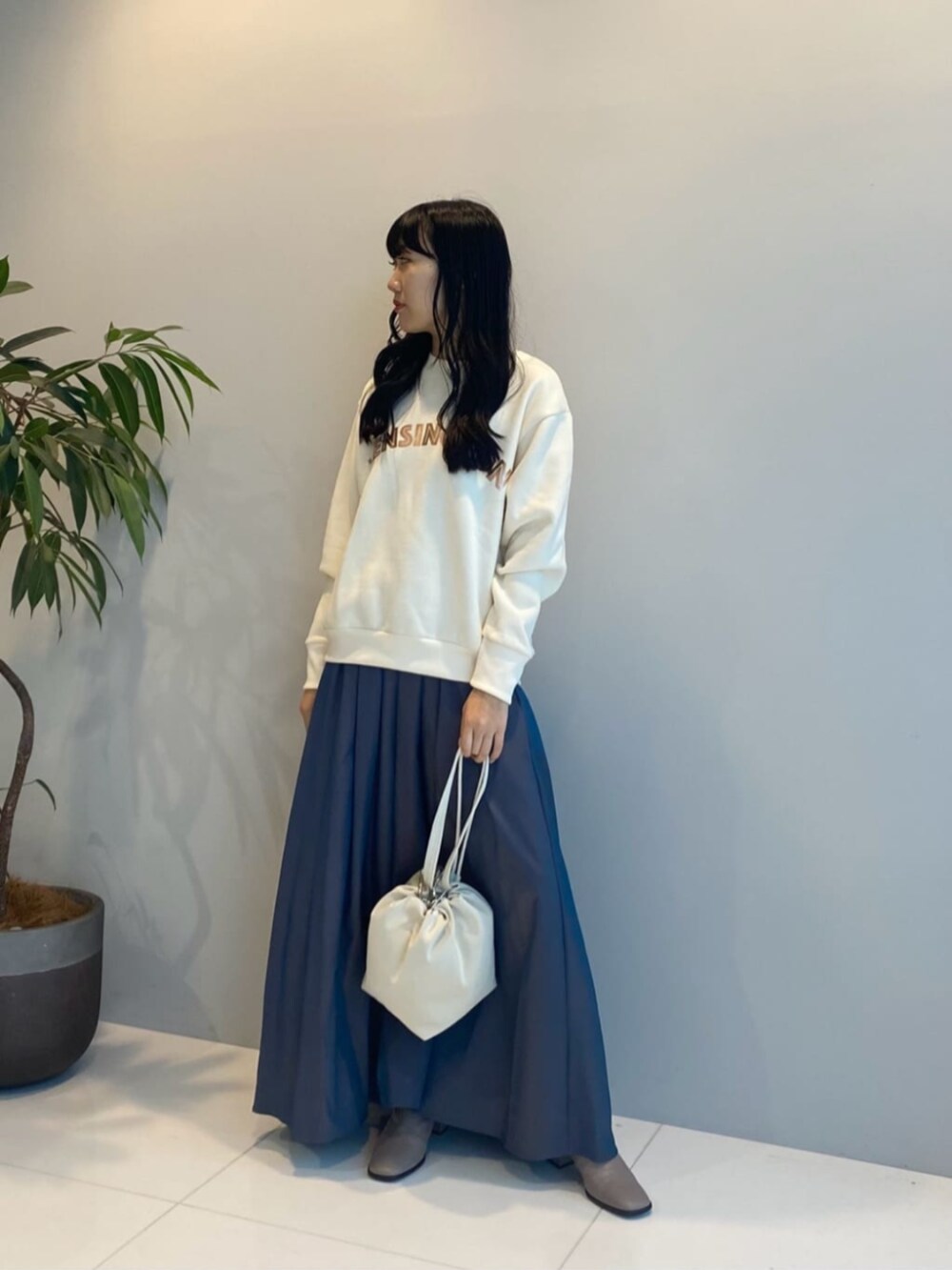 ホワイト系のハンドバッグ、ブルー系のスカート、ホワイト系のスウェットを着用したレディースの秋コーディネートの2枚目の写真