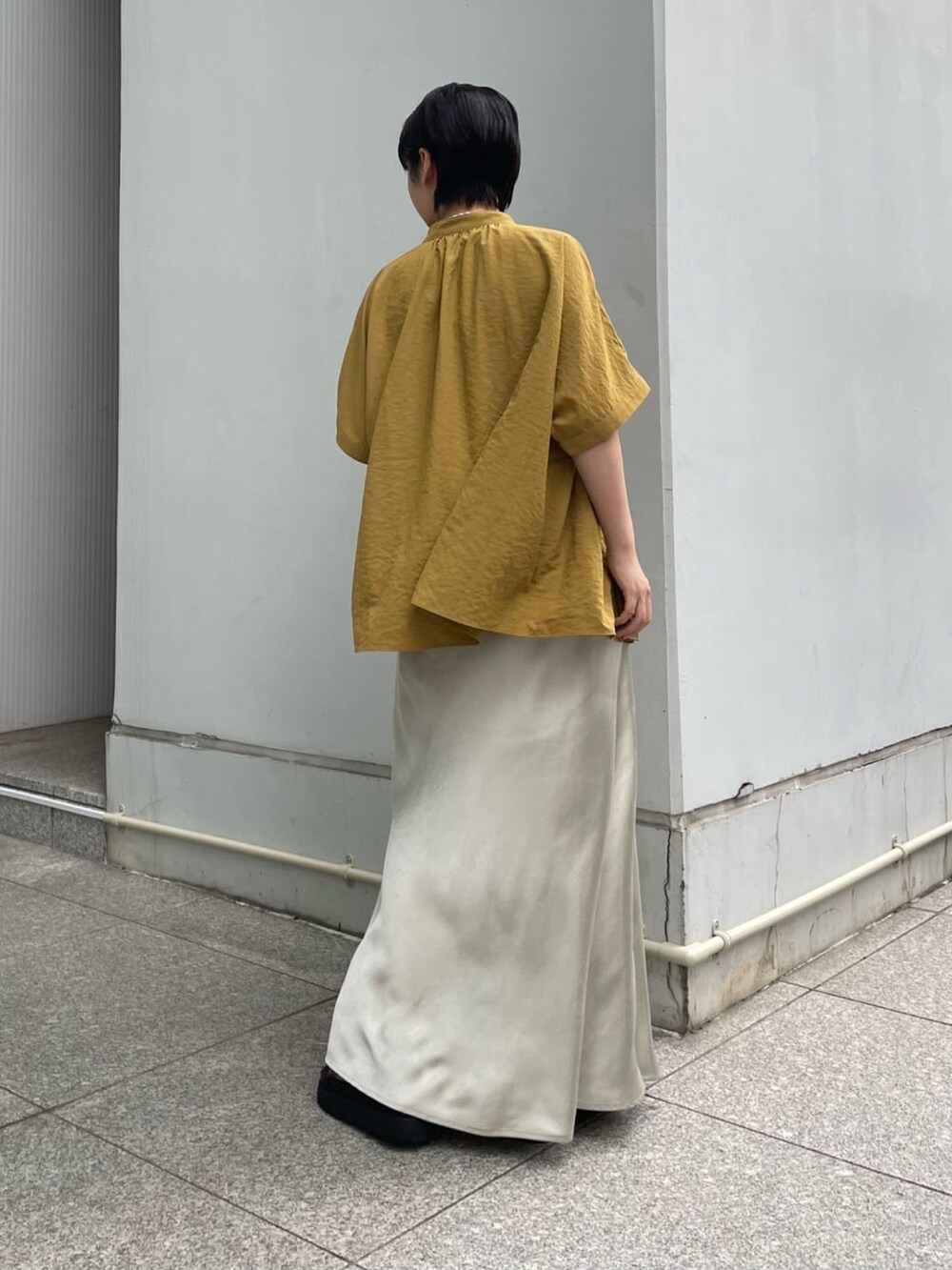 シルバー系のスカート、イエロー系のシャツ/ブラウス、ブラック系のサンダルを着用したレディースの夏コーディネートの2枚目の写真