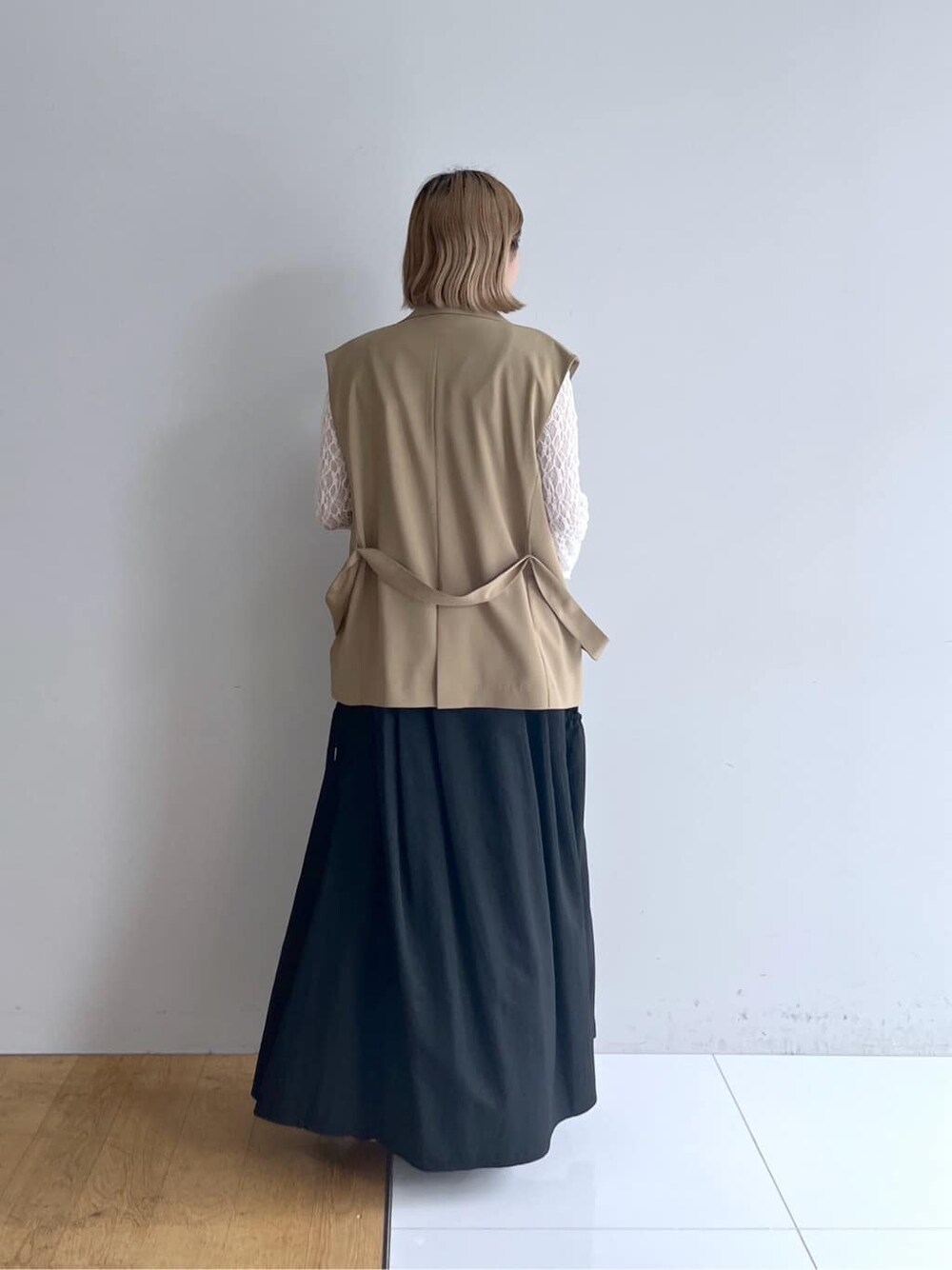イエロー系のベスト、ホワイト系のTシャツ/カットソー、グレー系のスカートを着用したレディースの春コーディネートの3枚目の写真