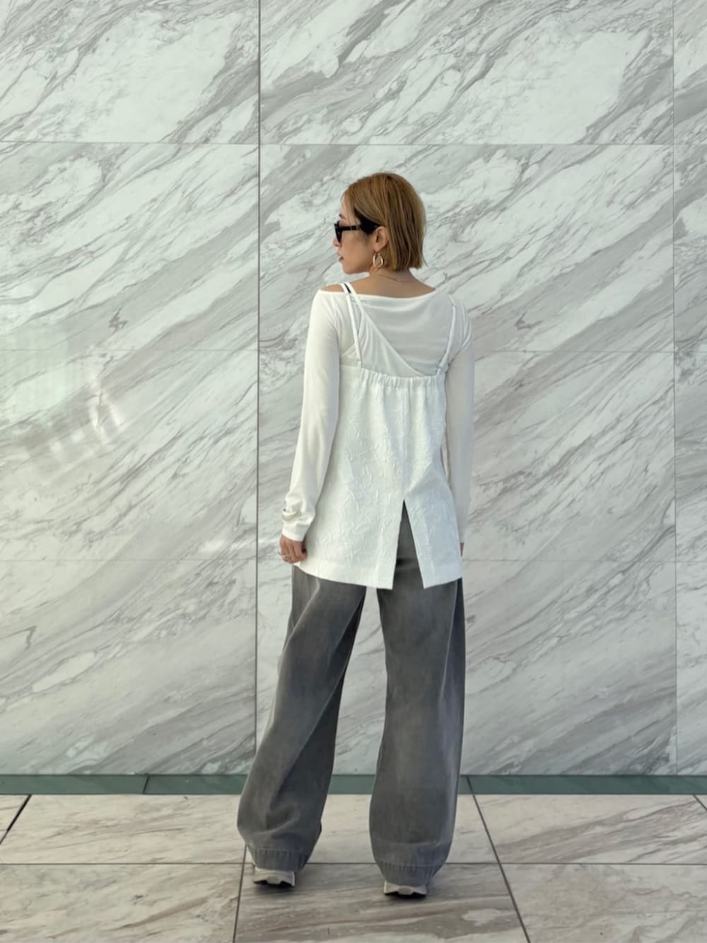 グレー系のデニムパンツ、ホワイト系のTシャツ/カットソー、ホワイト系のベストを着用したレディースの春コーディネートの3枚目の写真