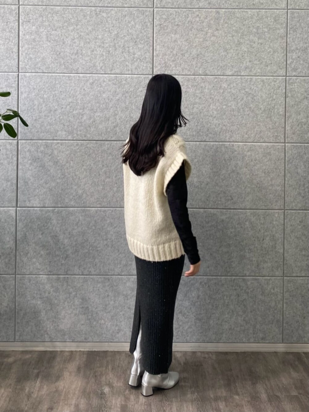 グレー系のスカート、ブラック系のTシャツ/カットソー、ホワイト系のベストを着用したレディースの冬コーディネートの3枚目の写真