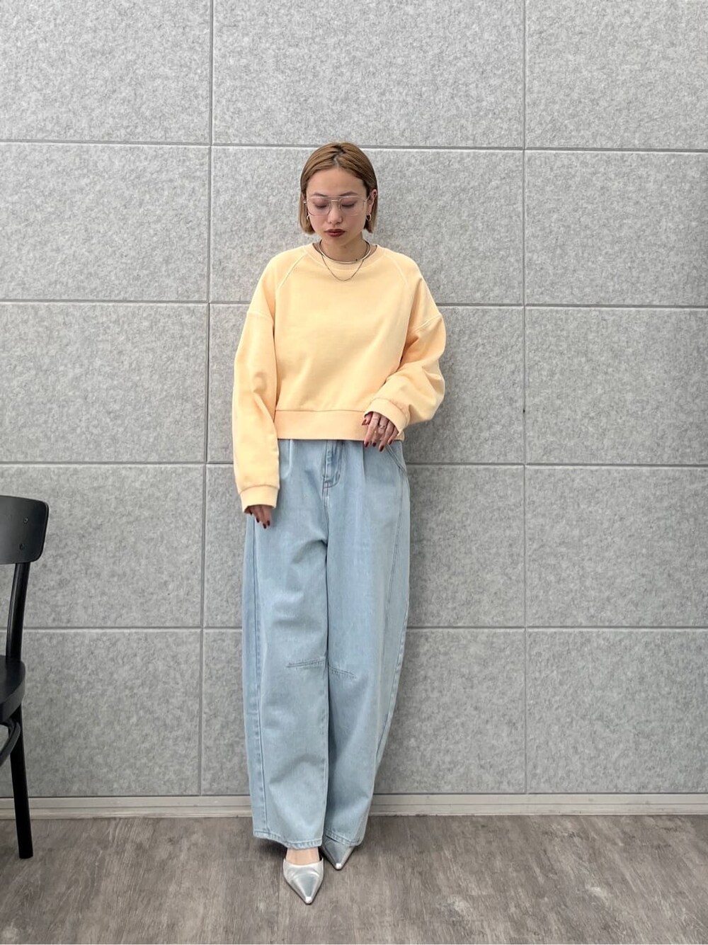 オレンジ系のスウェット、ブルー系のデニムパンツを着用したレディースの春コーディネートの9枚目の写真