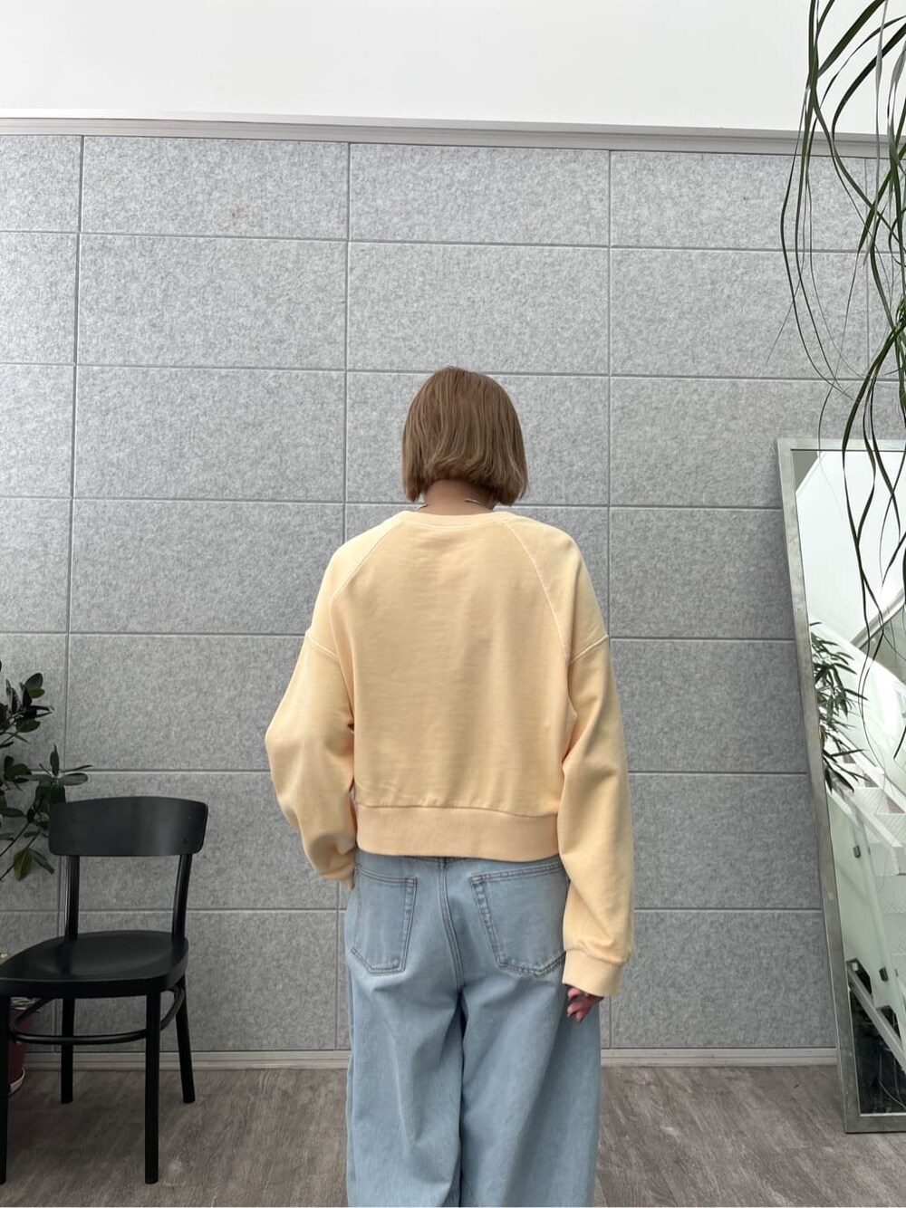 オレンジ系のスウェット、ブルー系のデニムパンツを着用したレディースの春コーディネートの8枚目の写真