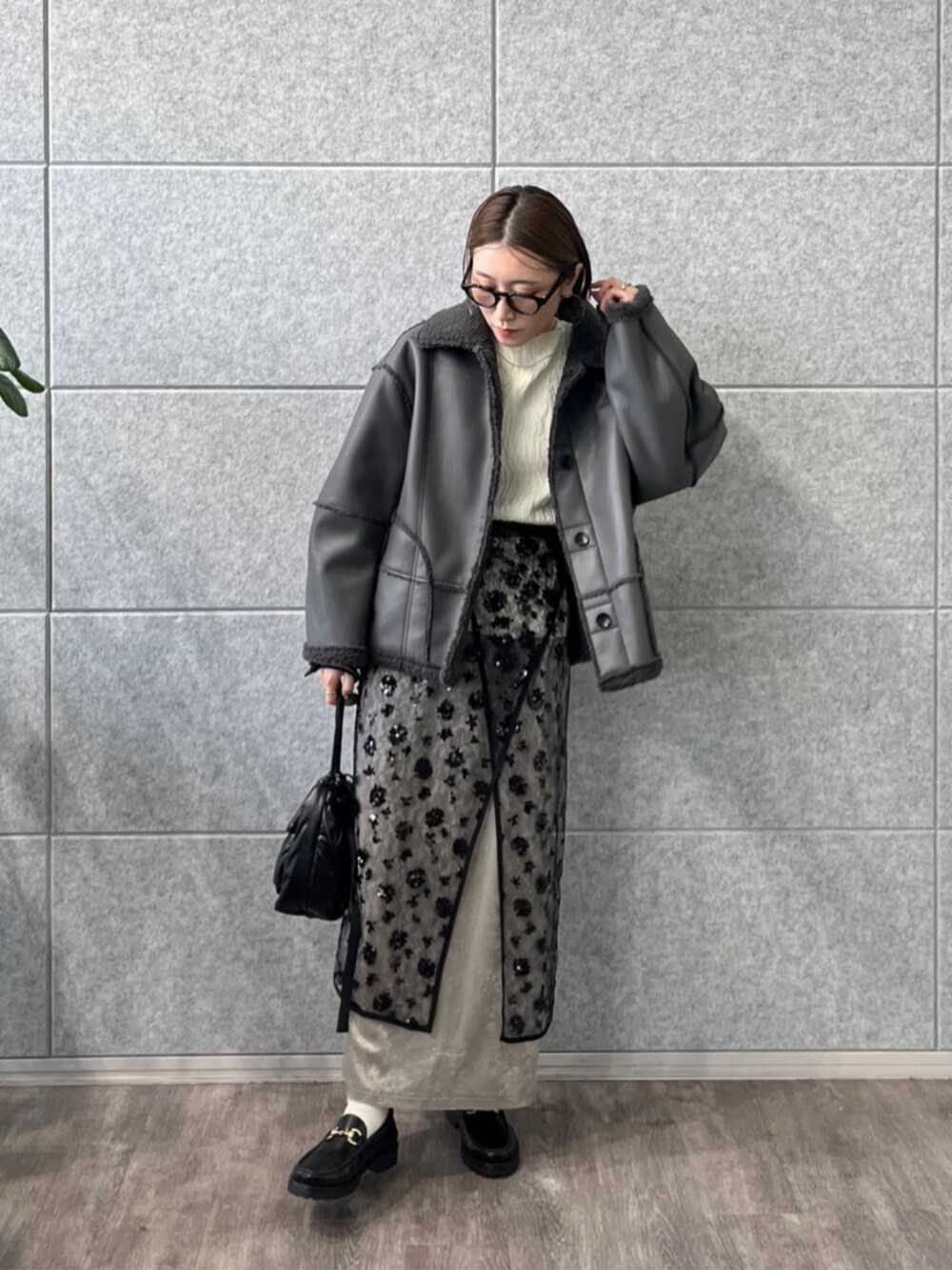 ブラック系のスカート、ホワイト系のニット/セーター、グレー系のブルゾンを着用したレディースの冬コーディネートの4枚目の写真