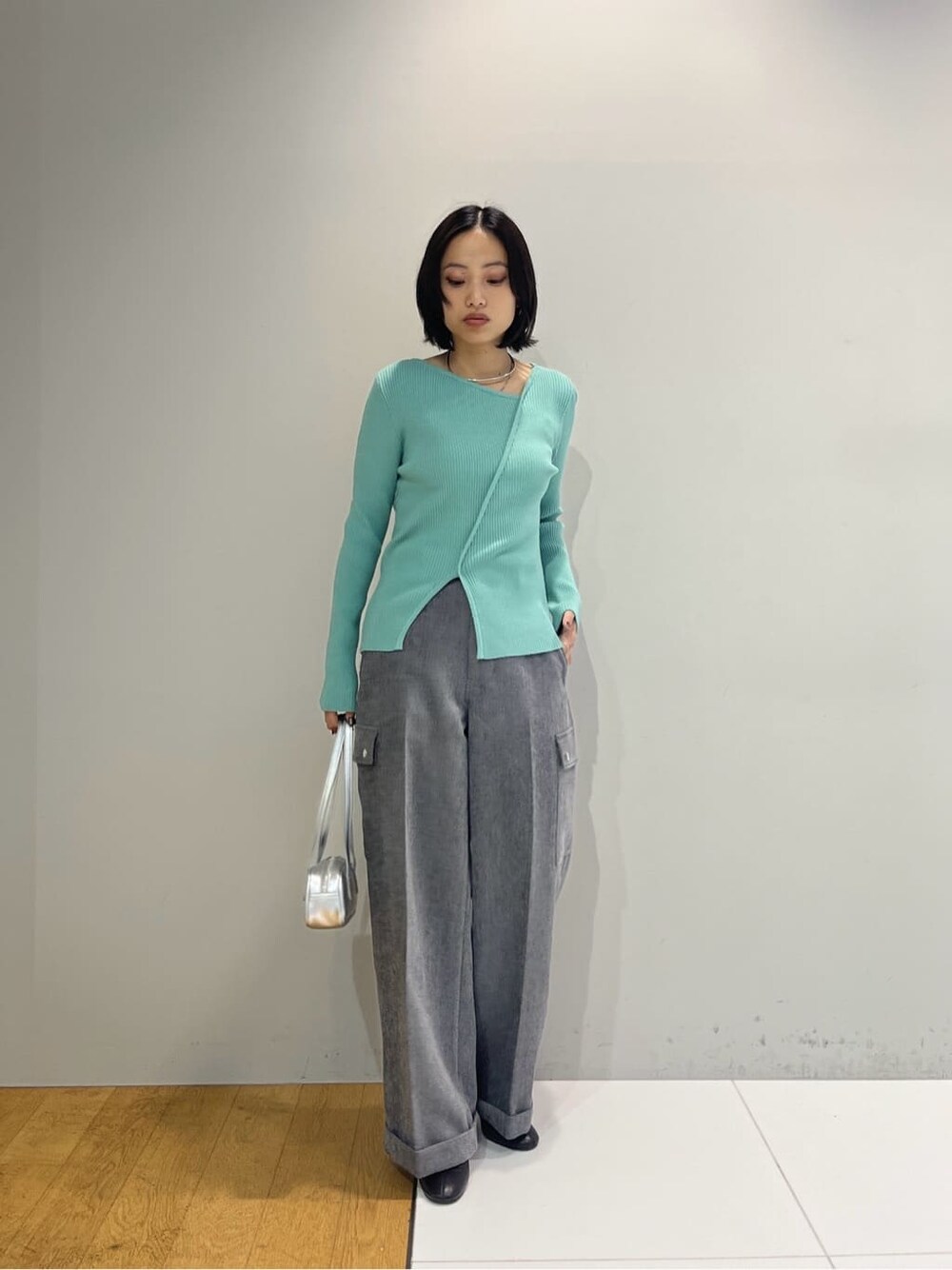 グリーン系のニット/セーター、グレー系のその他パンツ、シルバー系のハンドバッグを着用したレディースの秋コーディネートの7枚目の写真