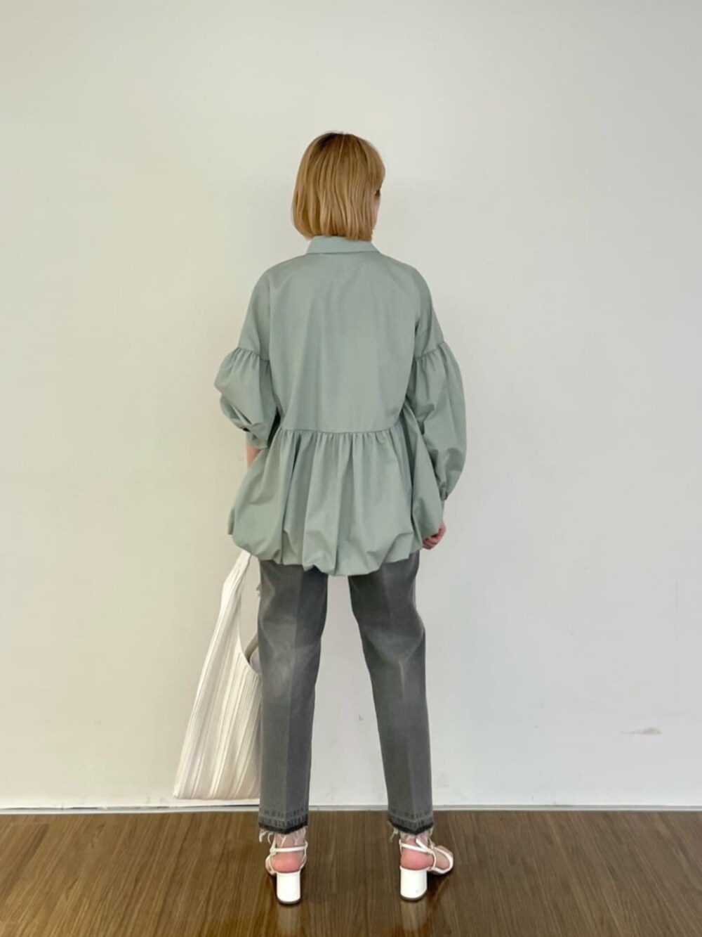 グレー系のデニムパンツ、グリーン系のシャツ/ブラウス、ホワイト系のトートバッグを着用したレディースの春コーディネートの3枚目の写真