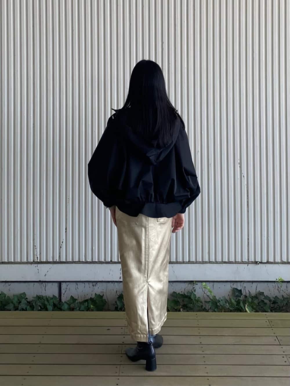 ブラック系のブルゾン、ゴールド系のスカート、ベージュ系のニット/セーターを着用したレディースの秋コーディネートの2枚目の写真