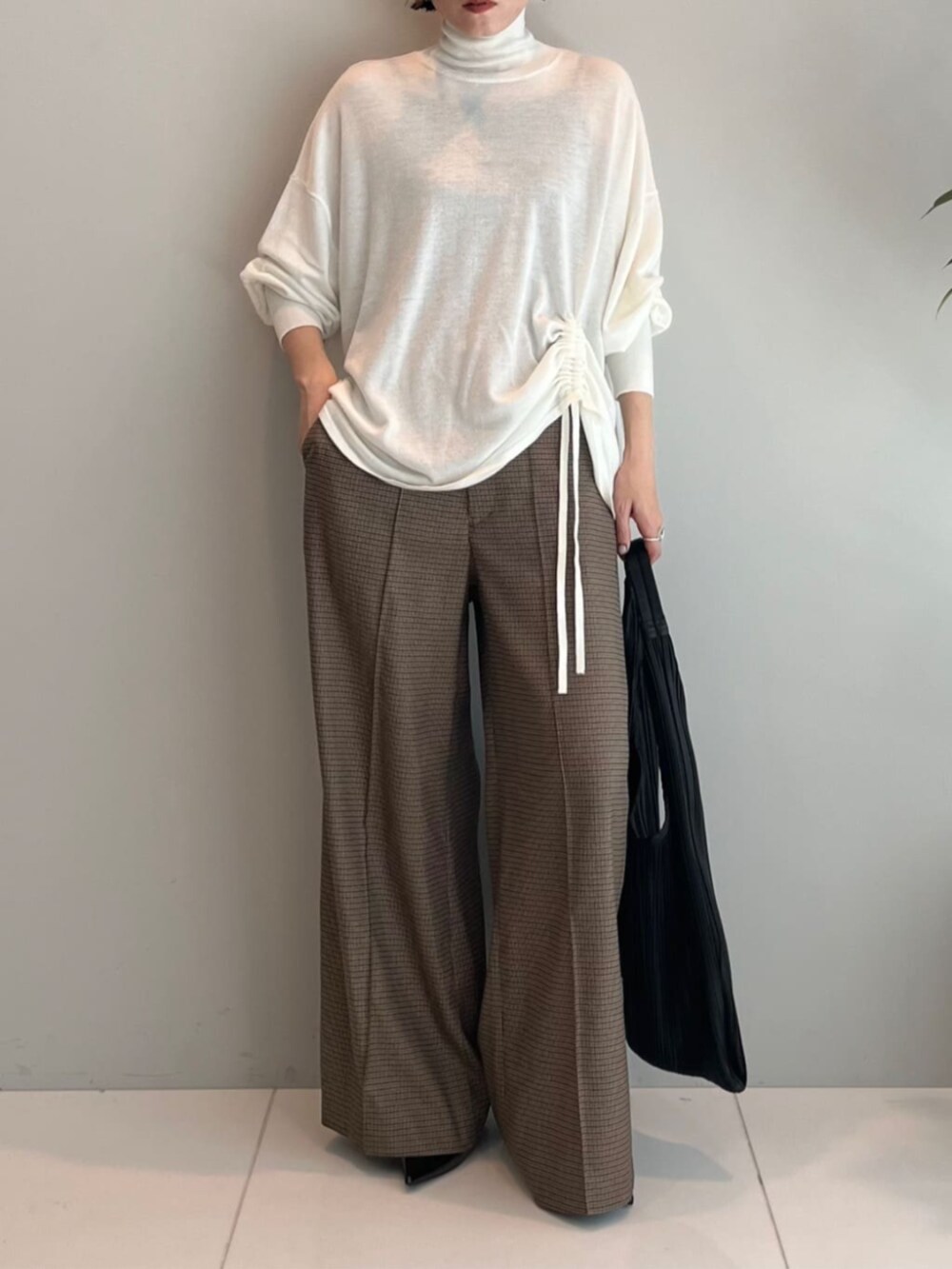 ホワイト系のニット/セーター、ベージュ系のその他パンツ、ブラック系のトートバッグを着用したレディースの秋コーディネートの3枚目の写真