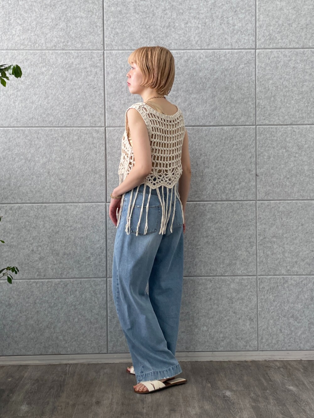 ホワイト系のベスト、ゴールド系のタンクトップ、ブルー系のデニムパンツを着用したレディースの春コーディネートの4枚目の写真