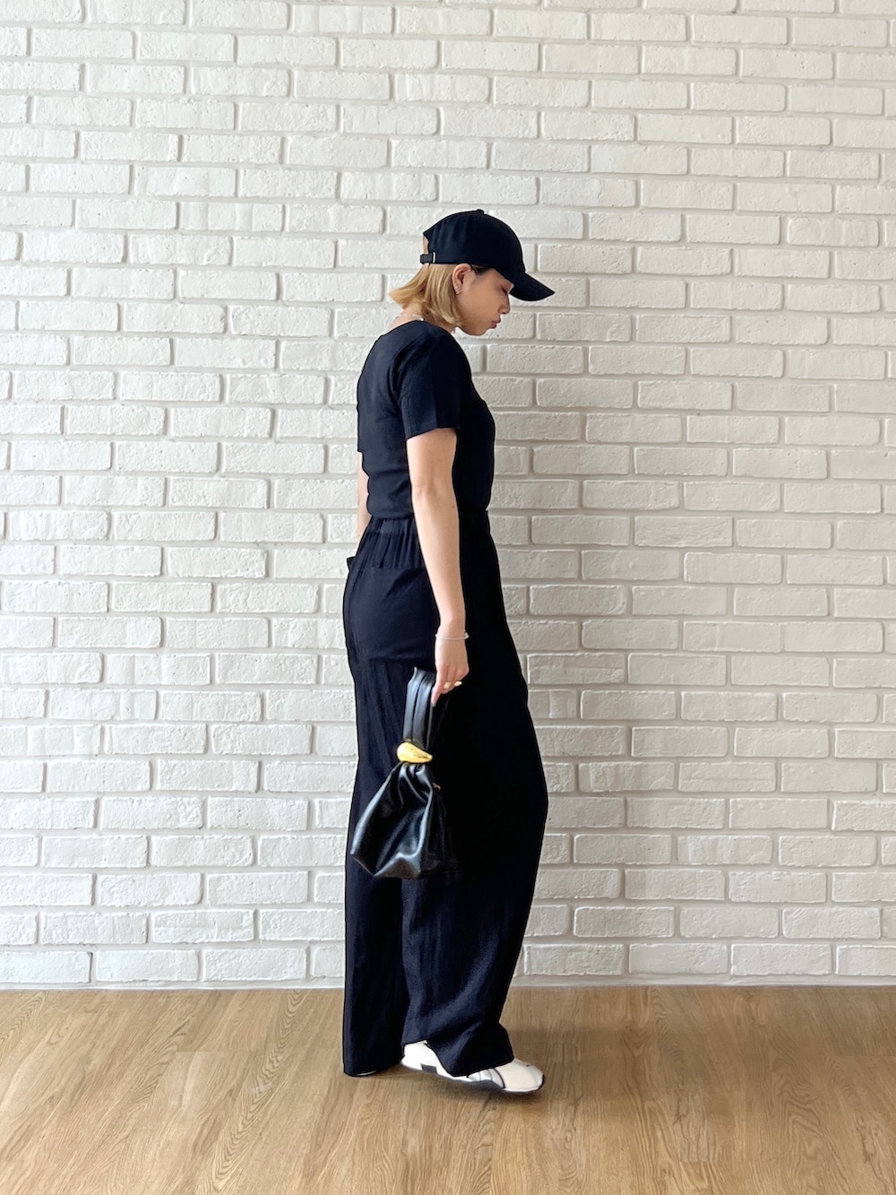 ブラック系のTシャツ/カットソー、ブラック系のその他パンツ、ホワイト系のスニーカーを着用したレディースの夏コーディネートの5枚目の写真