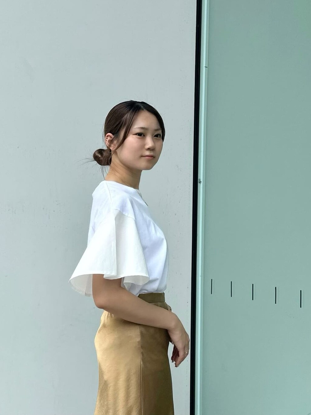 イエロー系のスカート、ホワイト系のサンダル、ホワイト系のTシャツ/カットソーを着用したレディースの夏コーディネートの2枚目の写真