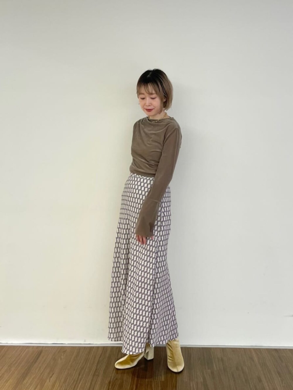 ベージュ系のスカート、ベージュ系のTシャツ/カットソーを着用したレディースの秋コーディネートの3枚目の写真