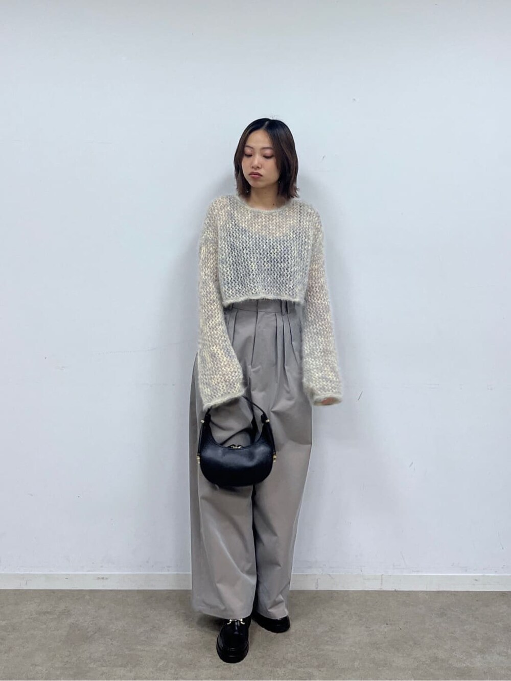ベージュ系のニット/セーター、グレー系のその他パンツ、ブラック系のショルダーバッグを着用したレディースの冬コーディネートの2枚目の写真