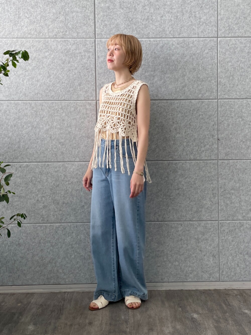 ホワイト系のベスト、ゴールド系のタンクトップ、ブルー系のデニムパンツを着用したレディースの春コーディネートの5枚目の写真