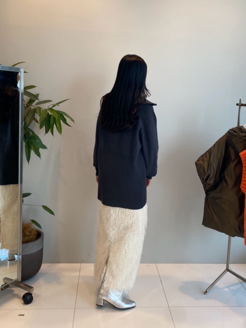 グレー系のニット/セーター、ホワイト系のスカートを着用したレディースの冬コーディネートの2枚目の写真