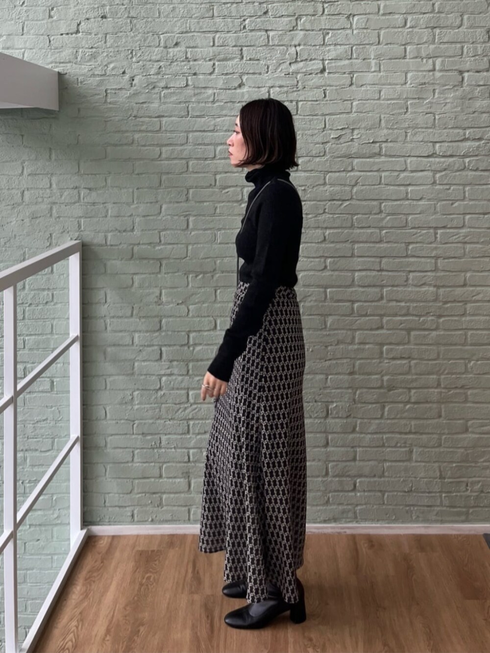 シルバー系のショルダーバッグ、ブラック系のスカート、ブラック系のニット/セーターを着用したレディースの秋コーディネートの3枚目の写真